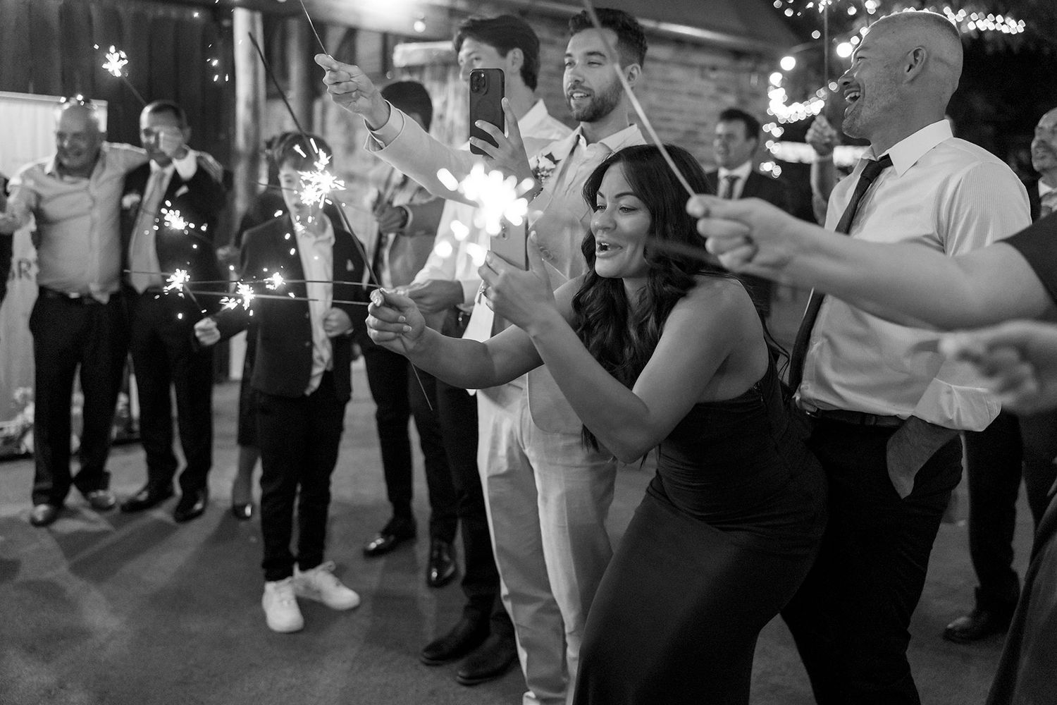 Wedding guests celebrate with sparklers at night as dancers move joyfully during an outdoor reception celebration at Brown Brothers Winery.