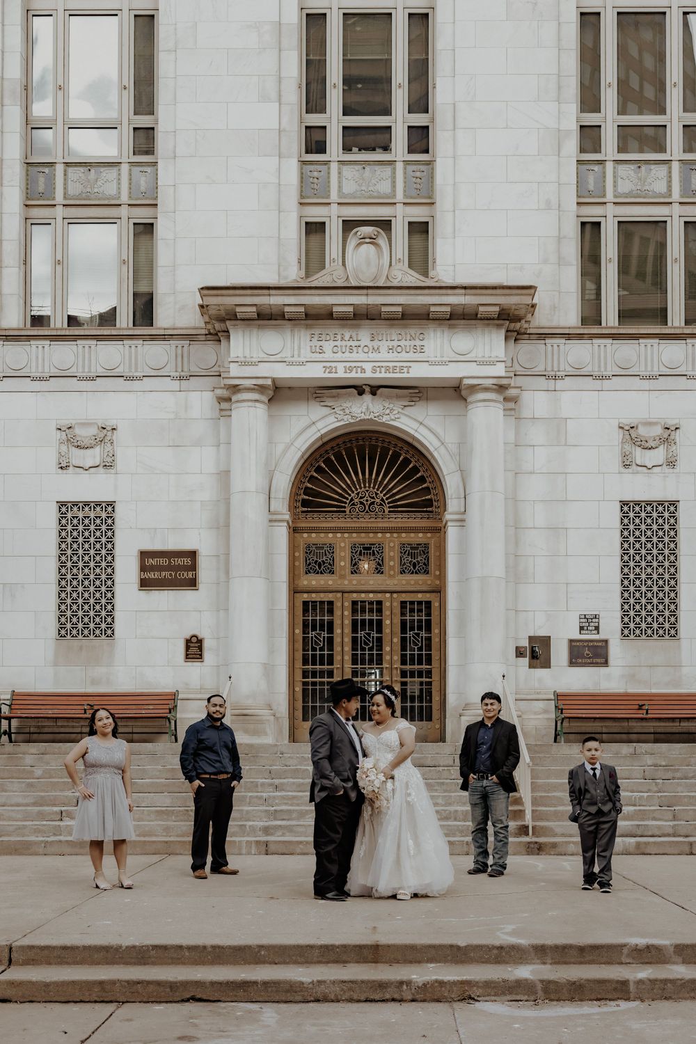 Bride and groom with their family posing in front of a building