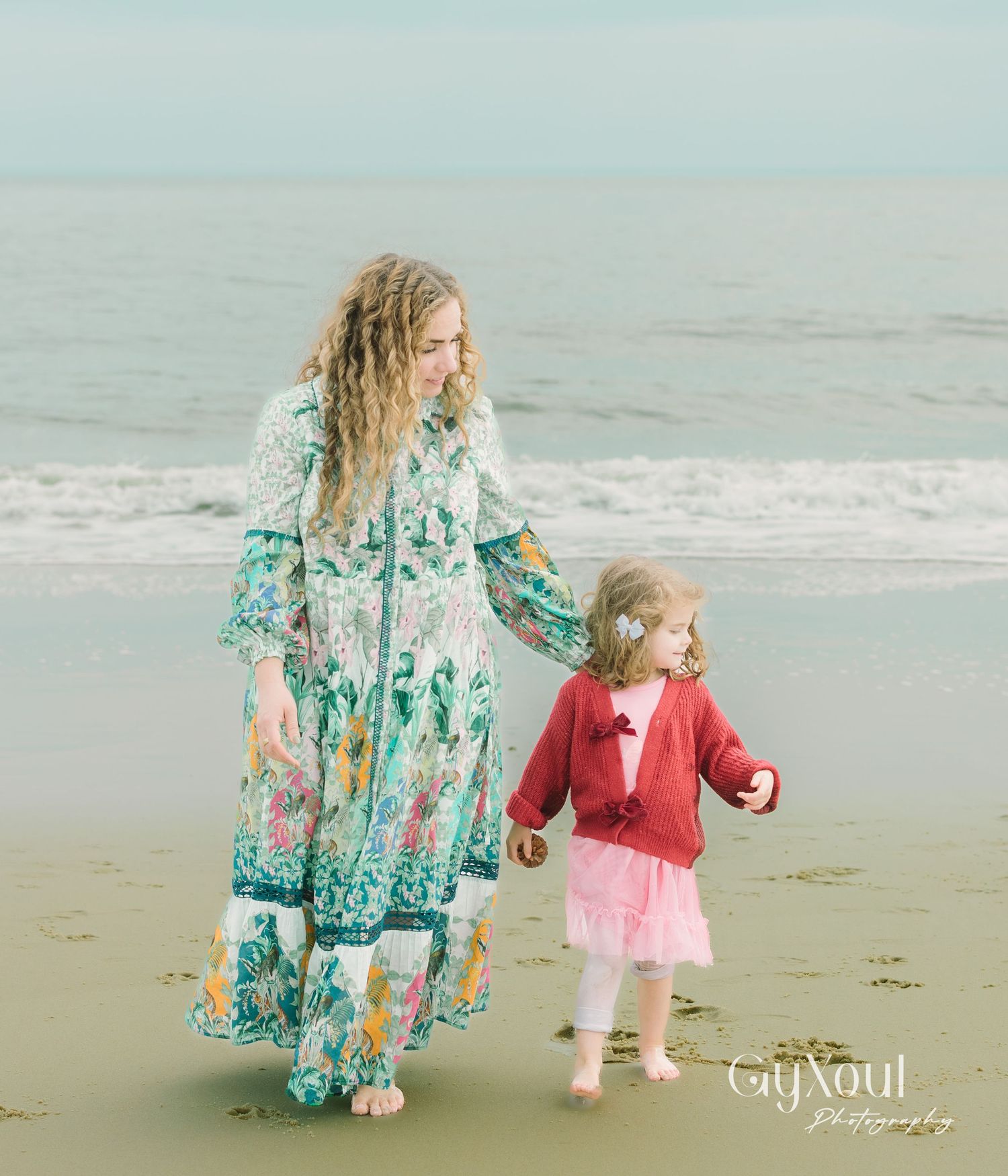 A scenic beach moment features a floral maxi dress and red sweater as figures stroll along the misty shoreline.