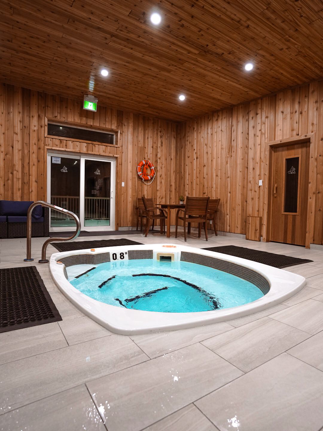 Modern indoor spa facility featuring a large hot tub with wood-paneled walls and recessed lighting.