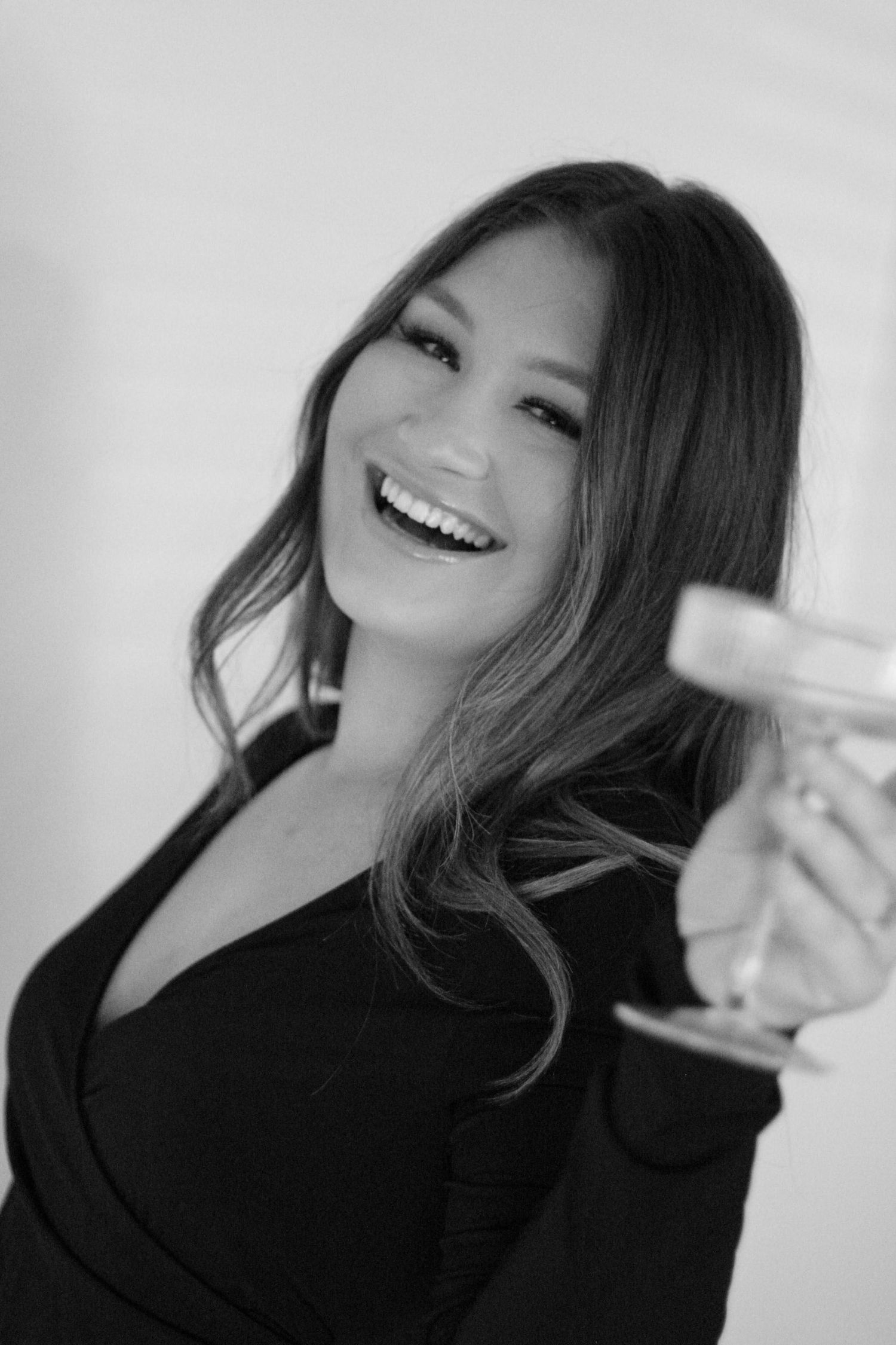 Black and white portrait of woman laughing joyfully while holding something off-camera.