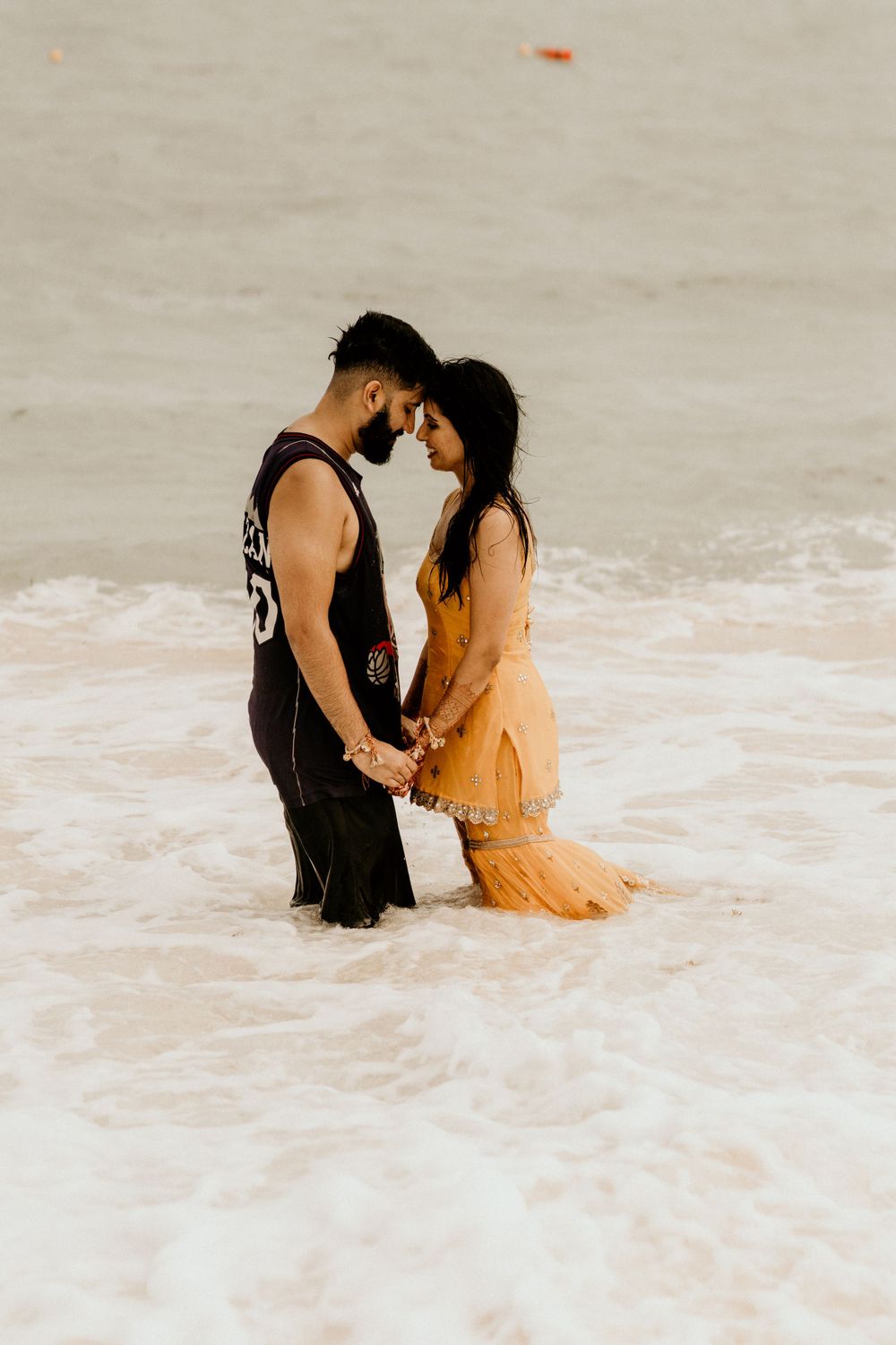 Romantic couple holding hands and sharing an intimate moment in the ocean surf.
