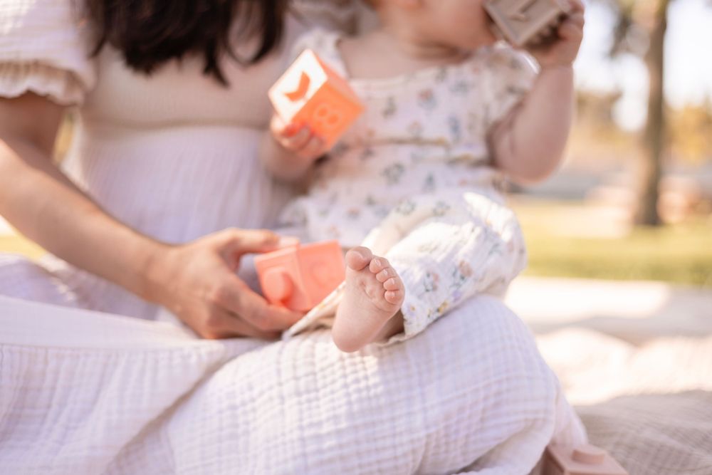 Close-up of baby girl's foot while sitting on mom's lap in this peaceful and special moment in the park in San Diego.