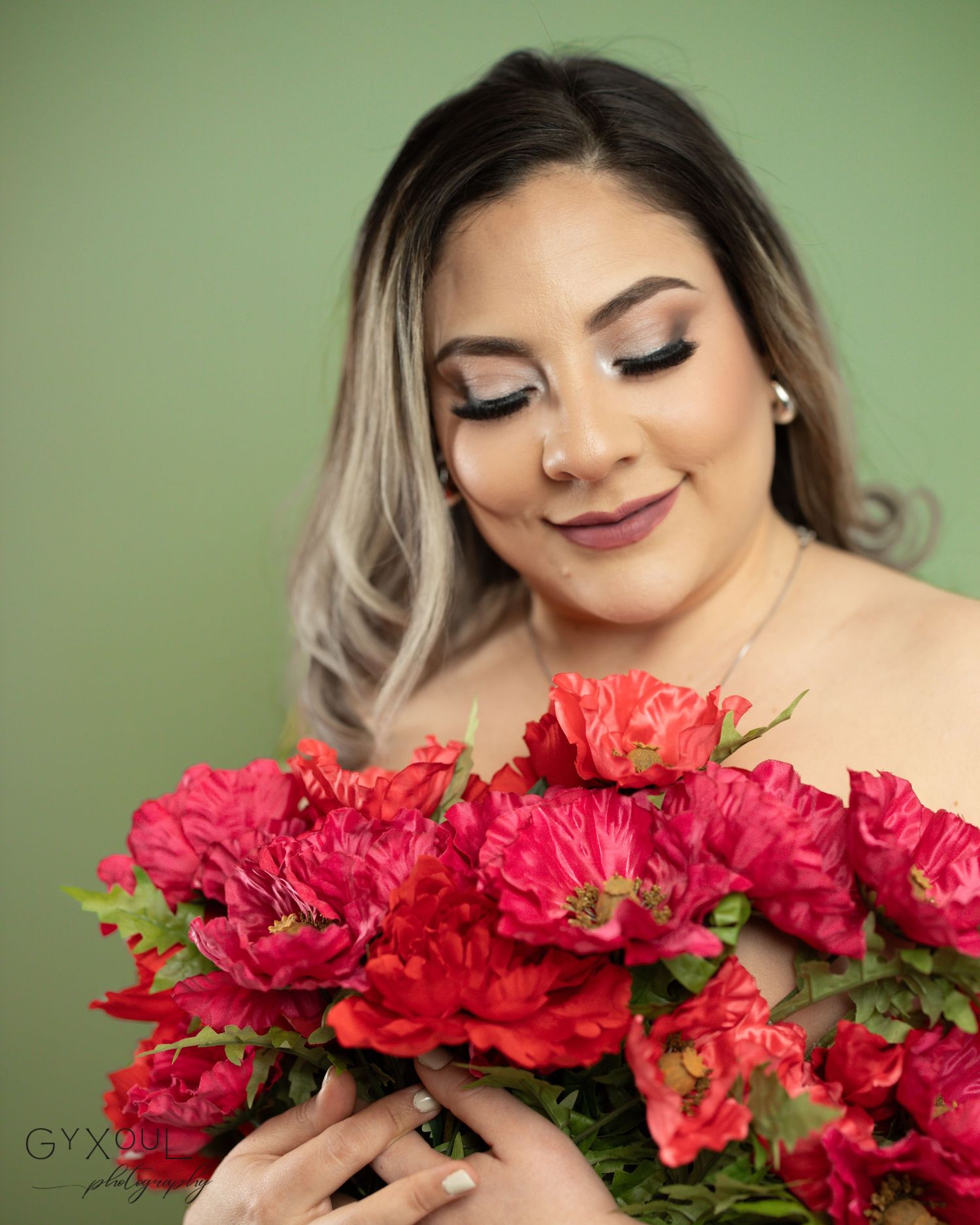 A portrait featuring bright red carnations against a green background with soft lighting and glamorous makeup.