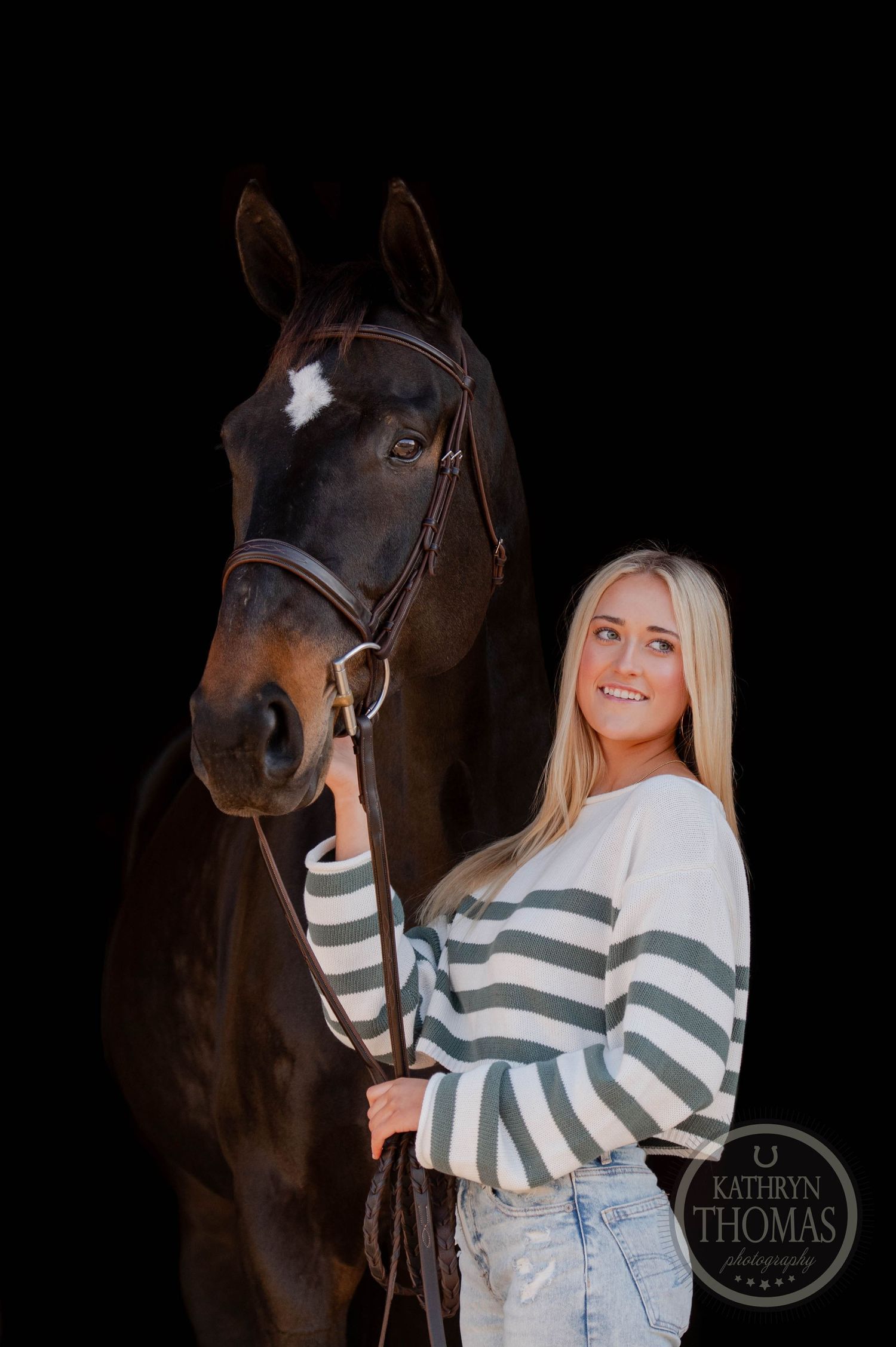 Dark bay horse and companion pose against black background in equestrian portrait with striped sweater.