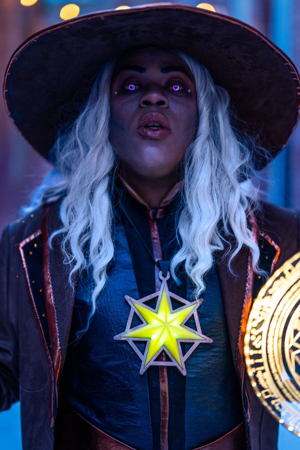 Dramatic portrait of fantasy character with white hair holding mystical shield under blue lights.