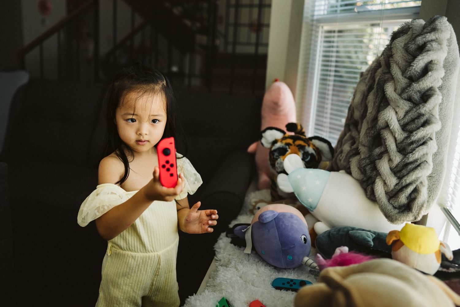 A playful scene with toys and stuffed animals arranged on furniture in a sunlit room.