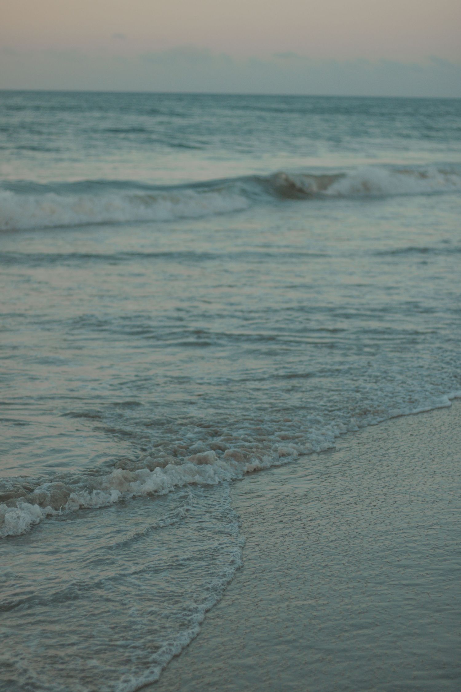 Tranquil ocean waves lapping at the shore during sunset.