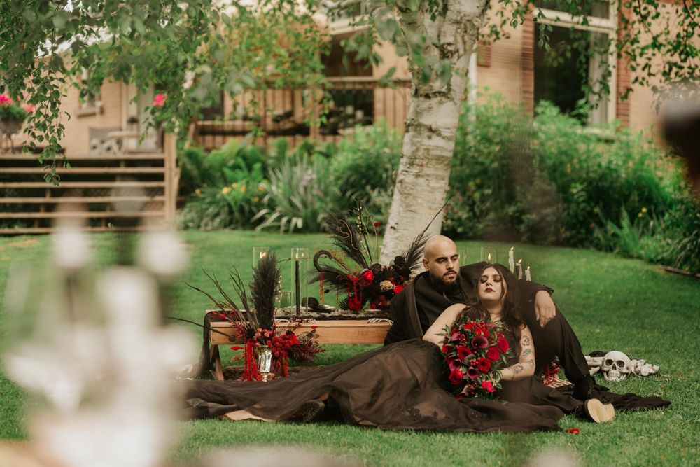 A cozy outdoor picnic setup in a garden with blankets, candles and autumn decor beneath a birch tree.