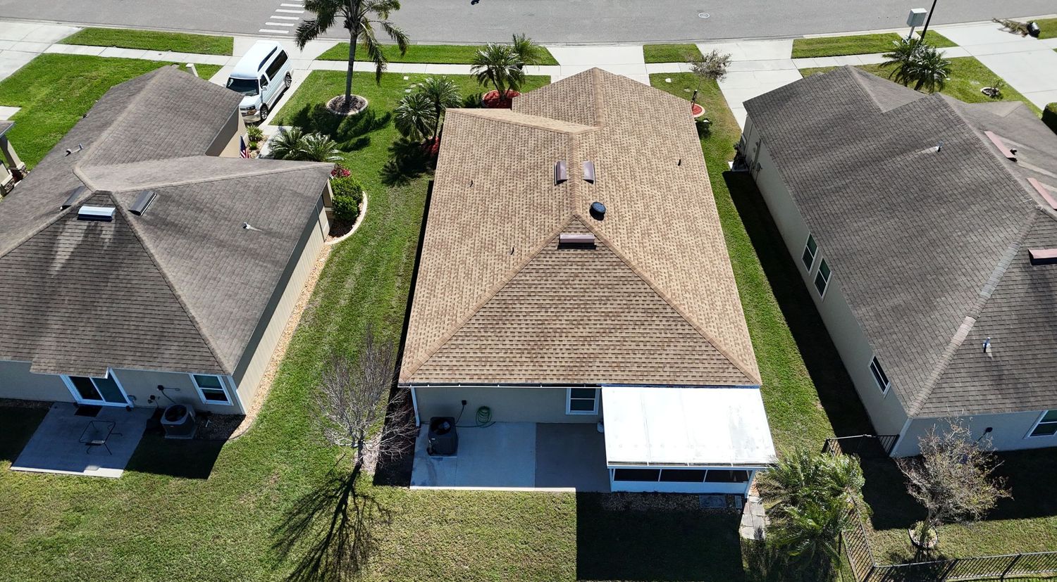 Drone photo of suburban houses with palm trees and rectangular swimming pools.
