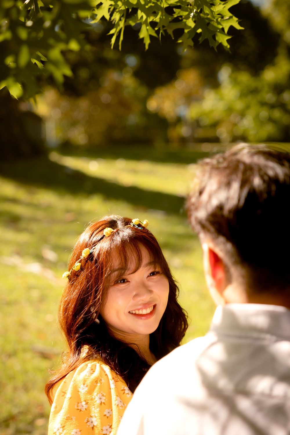 Two people sharing a romantic moment in a sun-dappled garden setting.