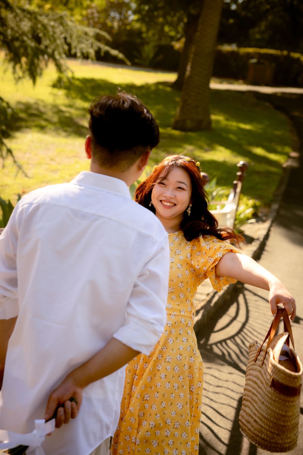 Two people in a romantic park scene, with a yellow dress and wicker basket.
