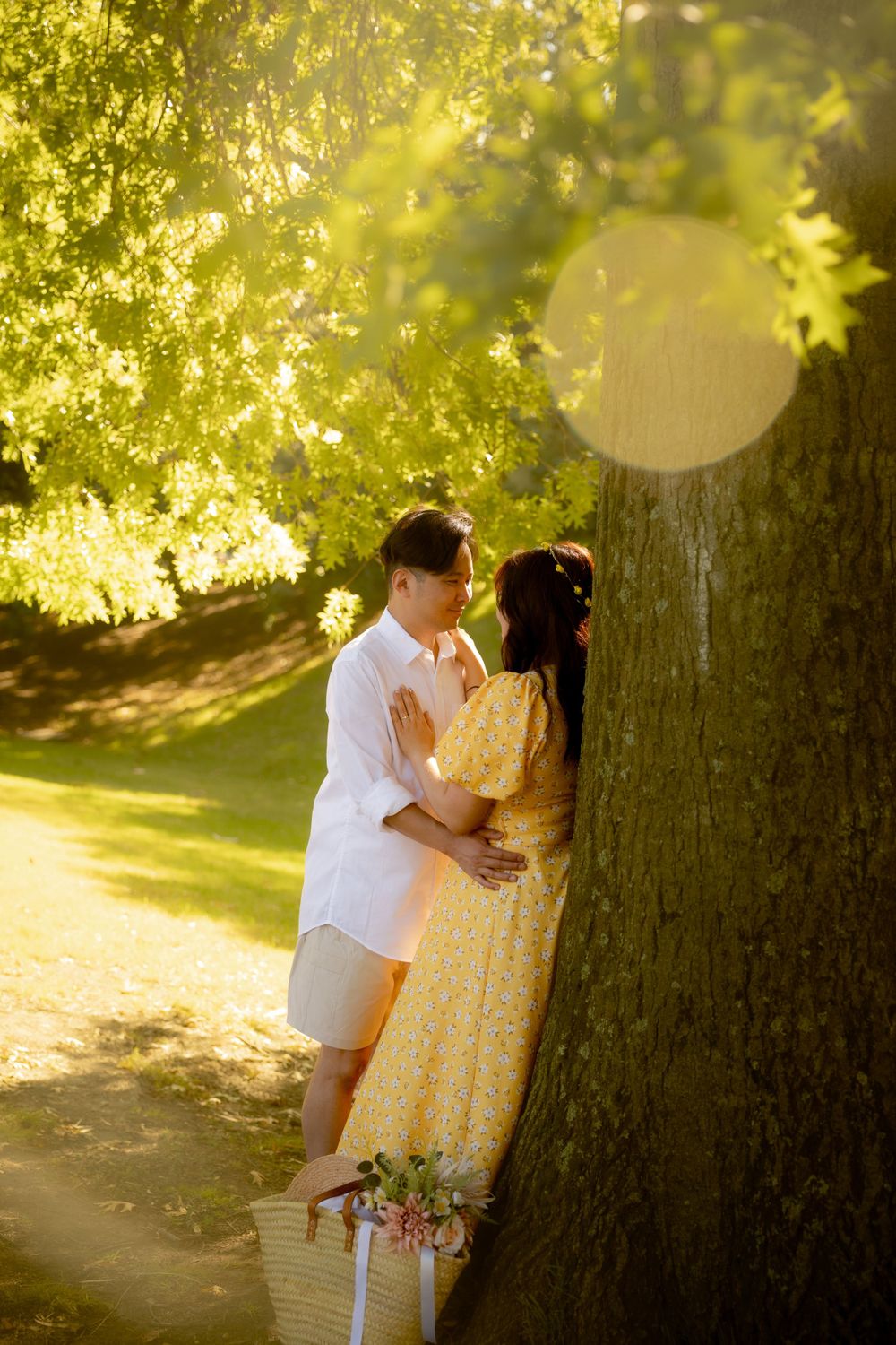 A romantic moment captured against a tree in golden afternoon light.