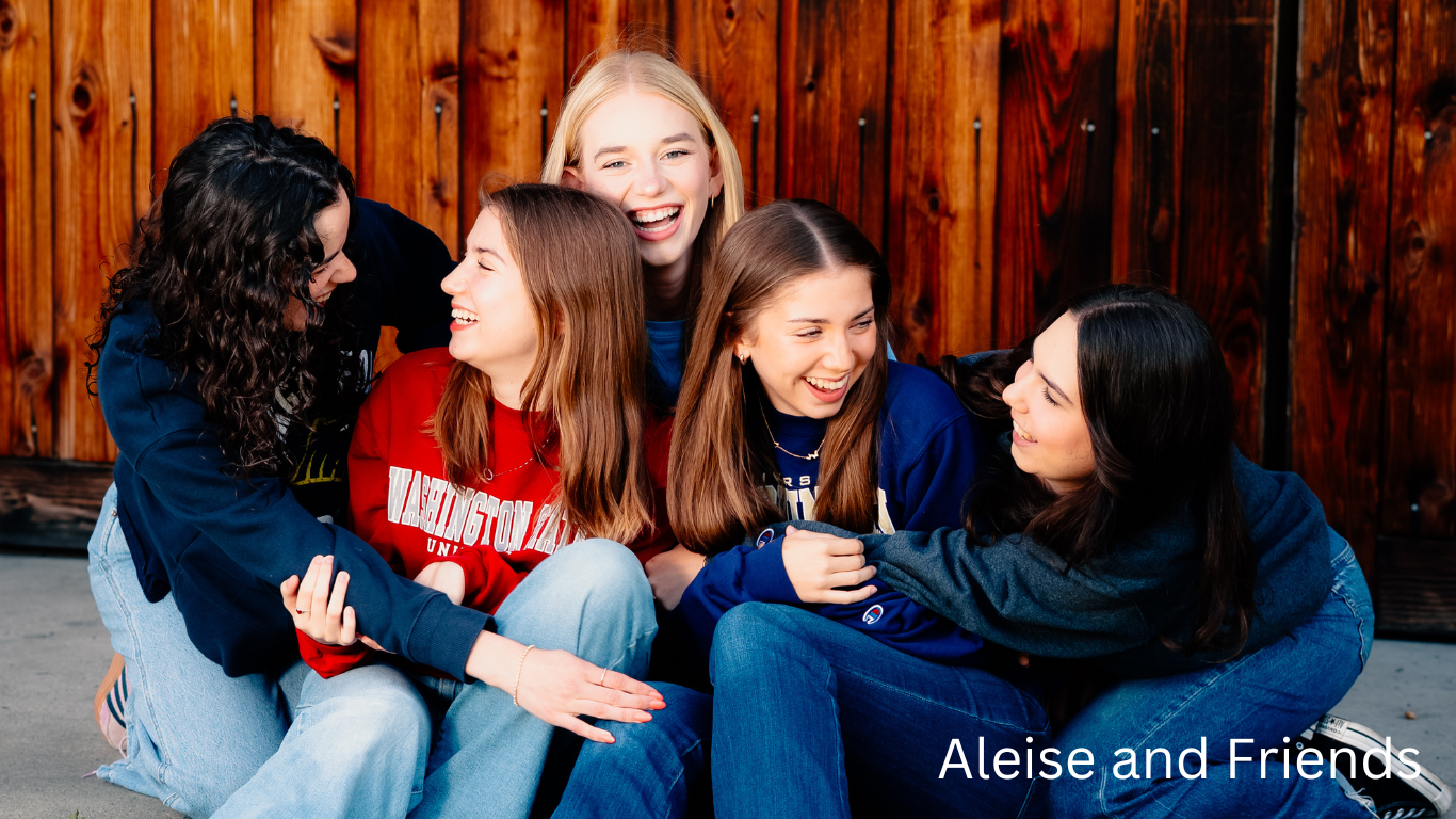 A group enjoying a casual moment together sitting on steps against a wooden wall.