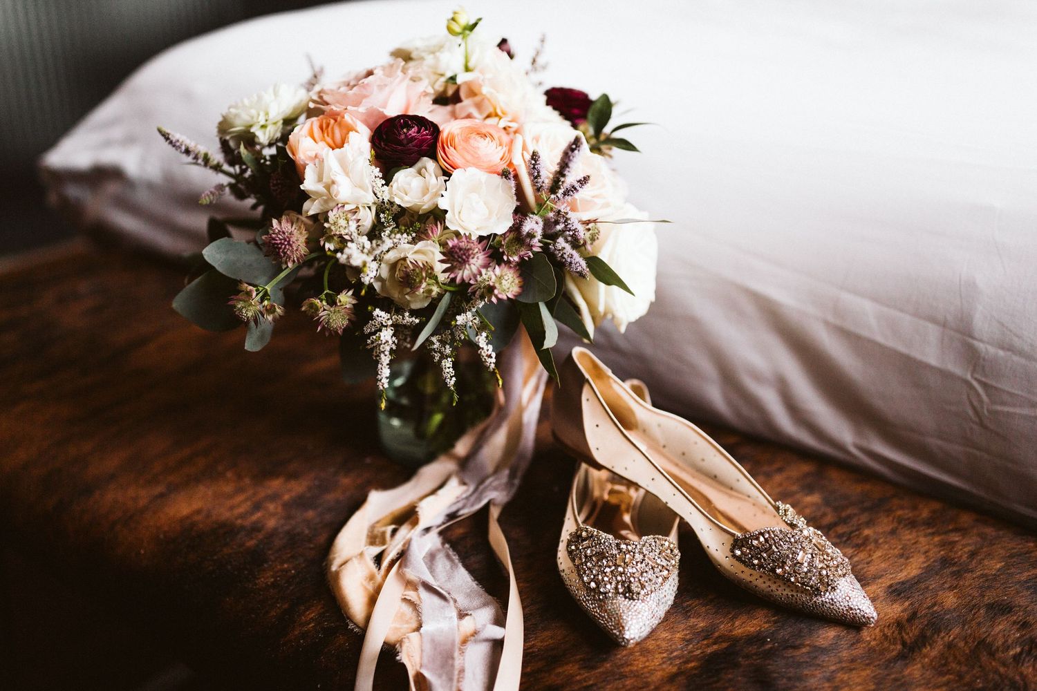 Elegant wedding details including pink roses, silk ribbons, and delicate floral arrangements on white linens.