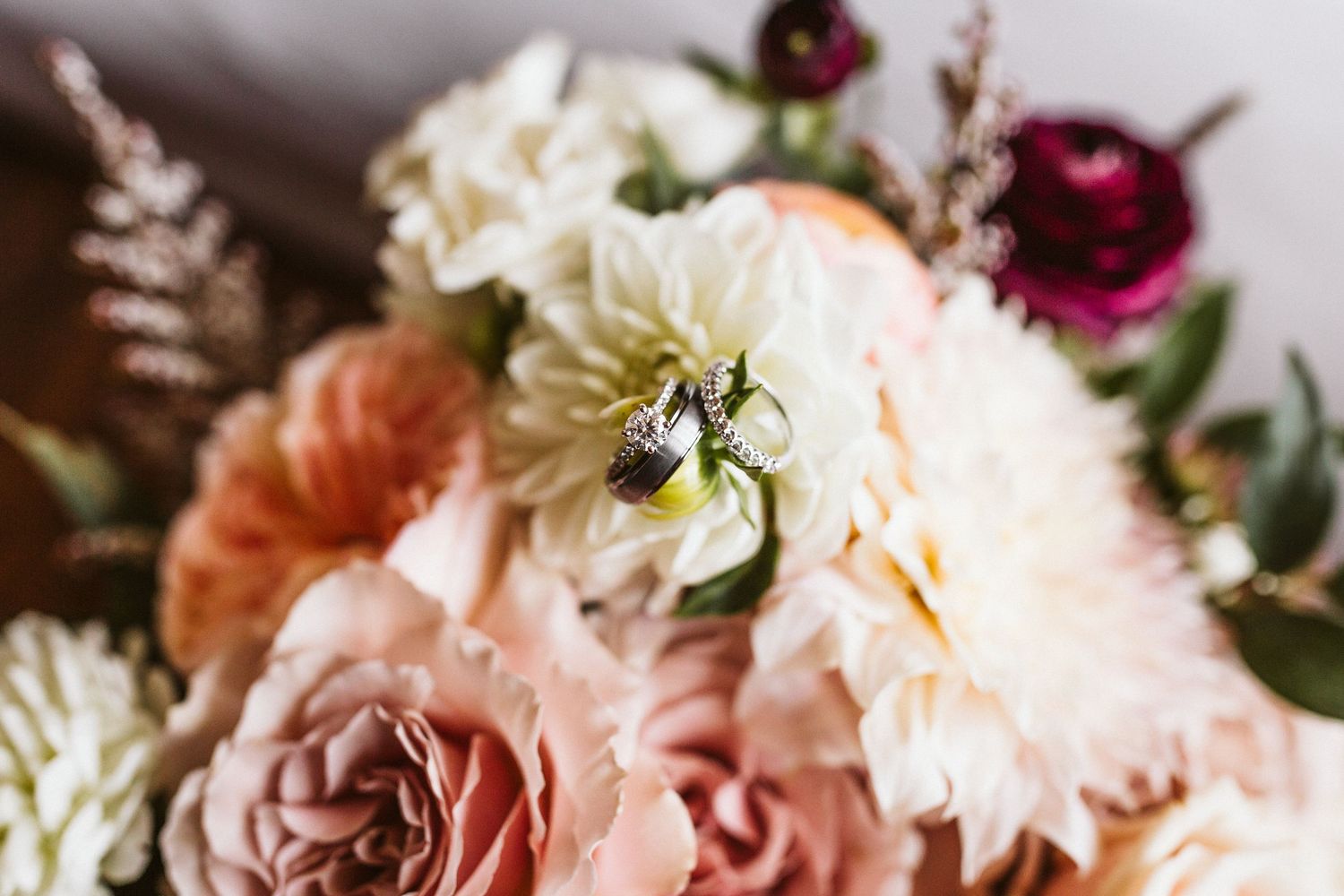 Romantic floral arrangement featuring pink and cream dahlias with deep burgundy accents and delicate greenery.
