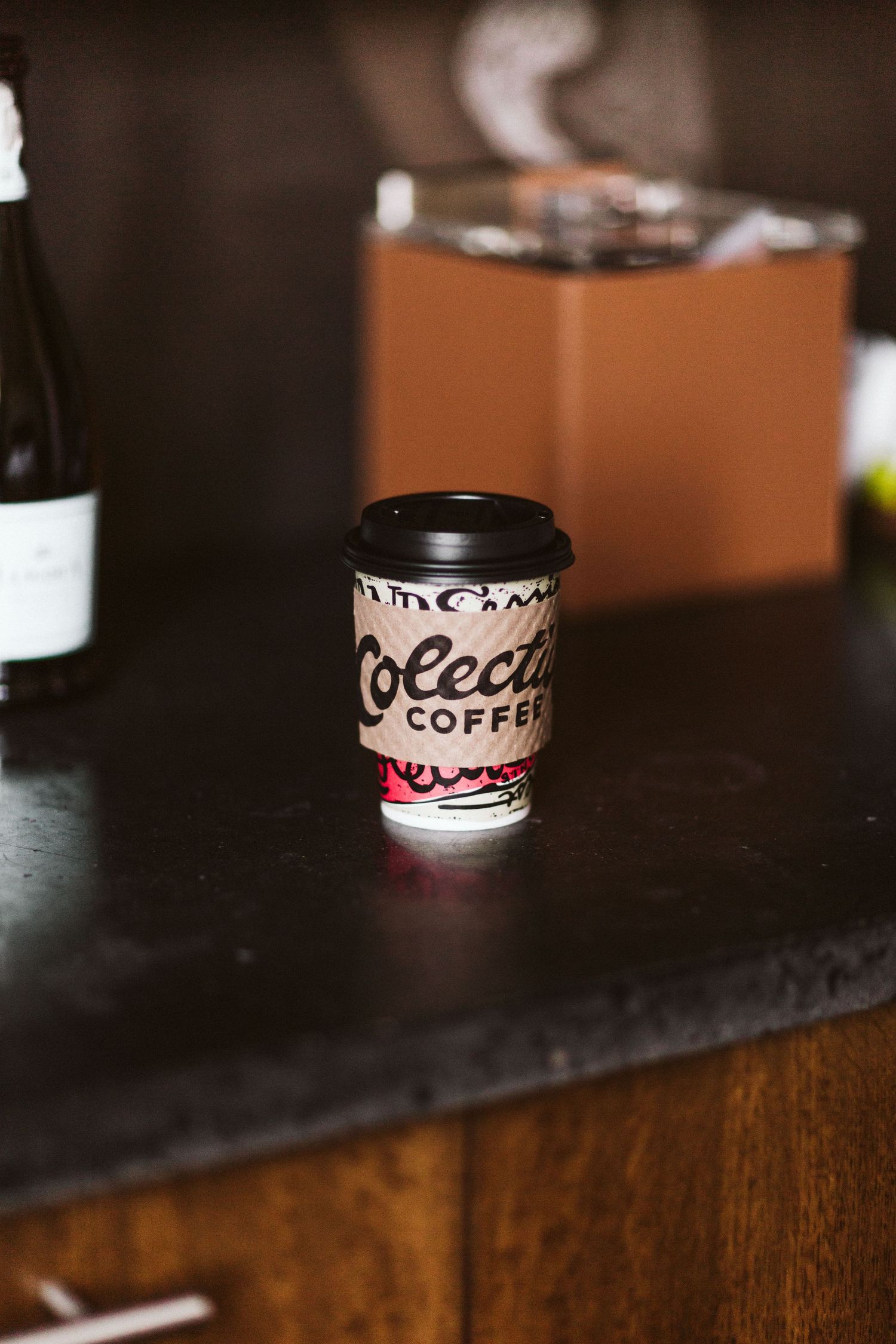 Row of Dream Coffee branded paper cups lined up on dark wooden surface.