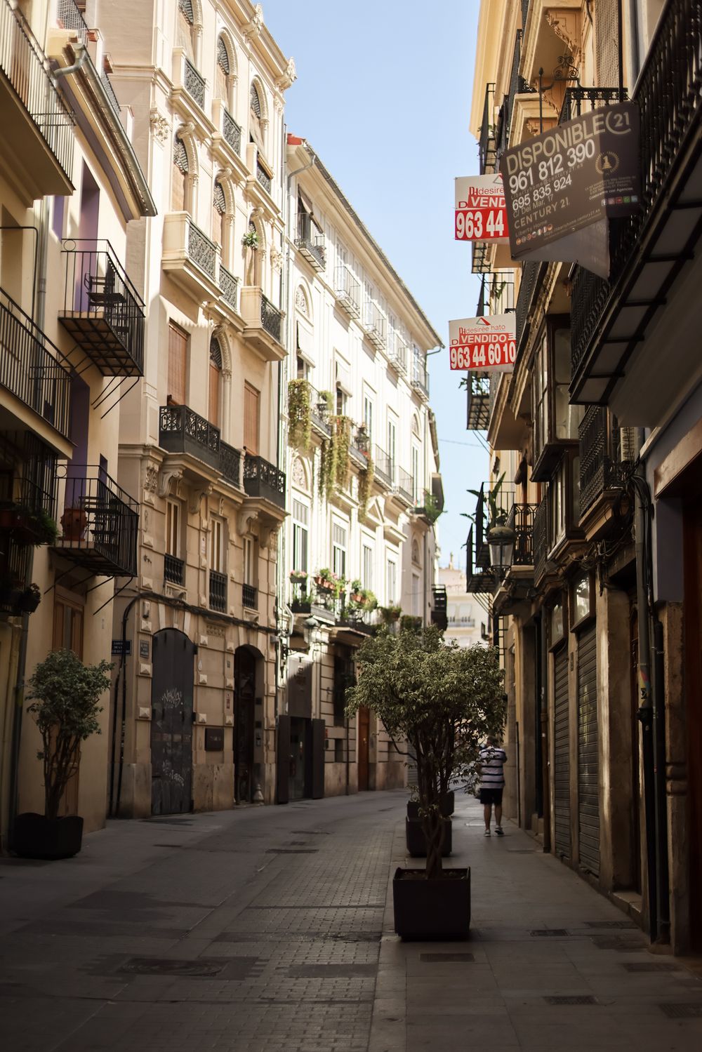 Historic narrow cobblestone street lined with ornate European buildings and balconies in an old city center.