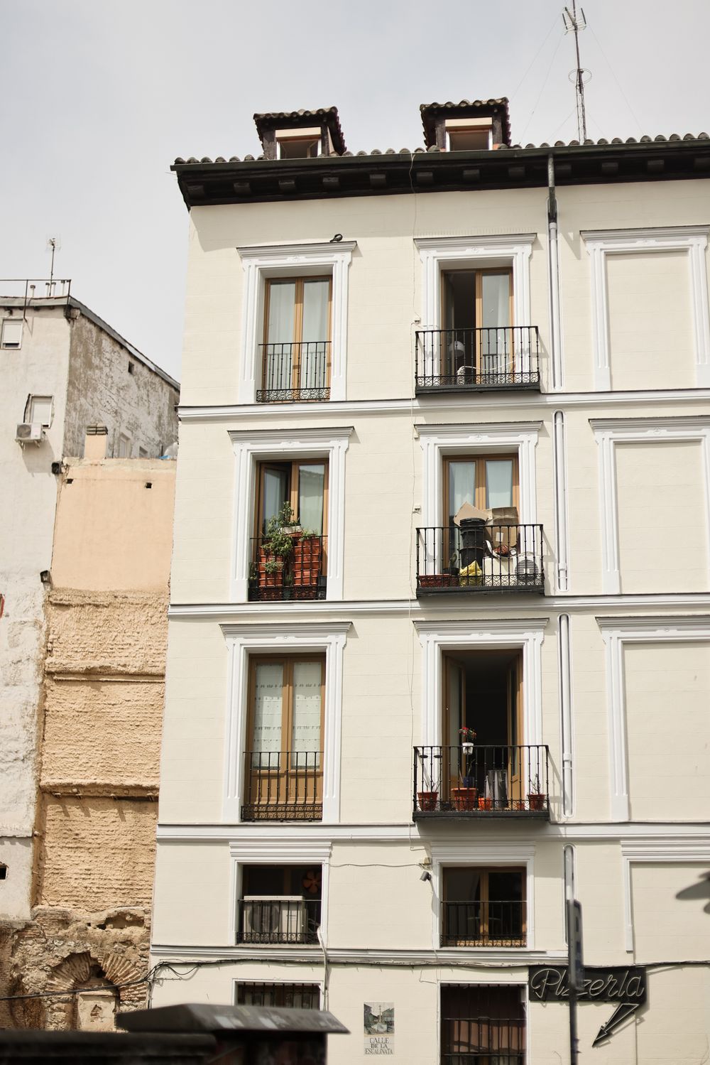 Traditional white apartment building in Madrid with wrought iron balconies and decorative dormers on the top floor.