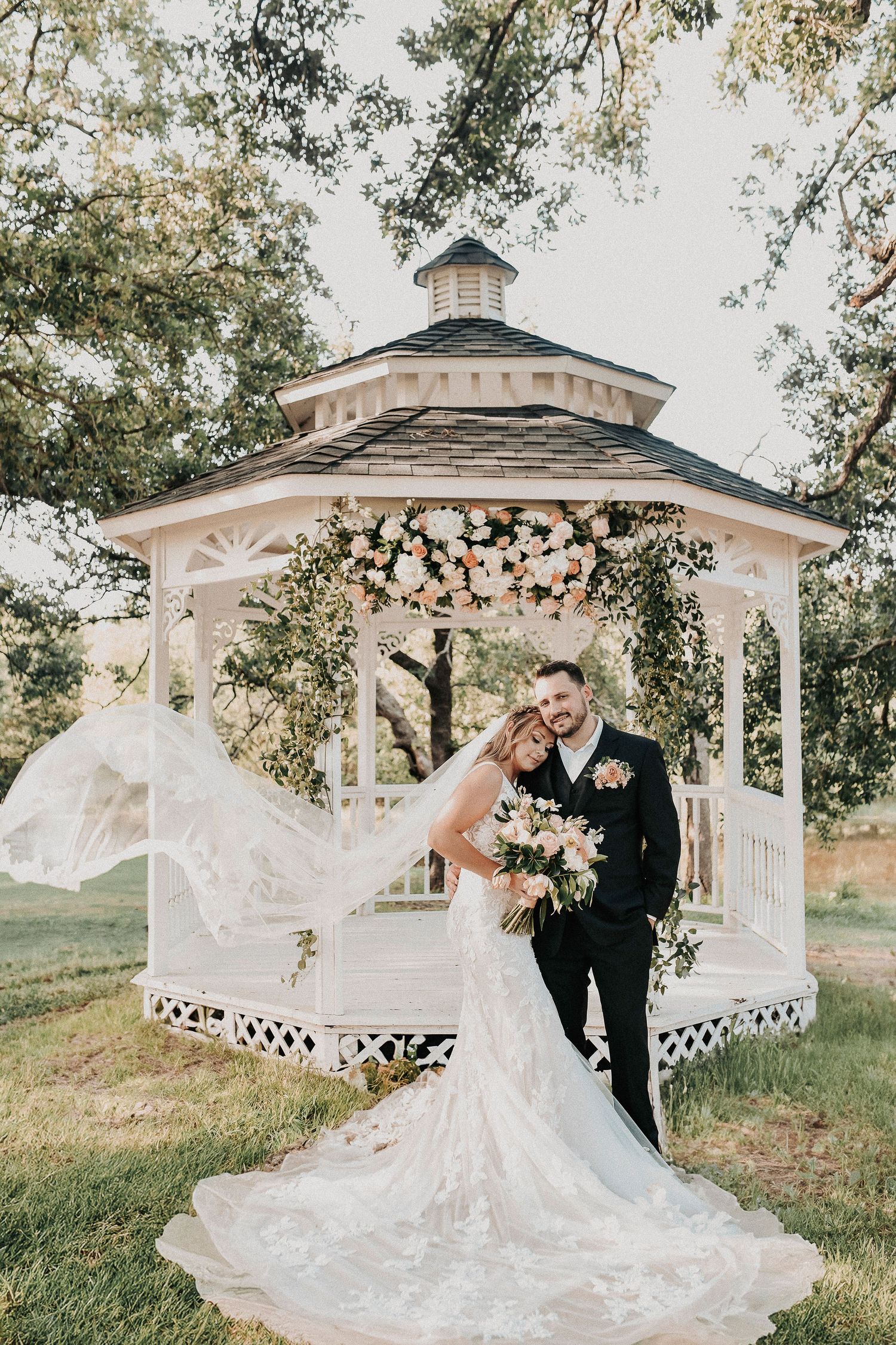 Couple interacting naturally during spring wedding portraits beneath oak trees.