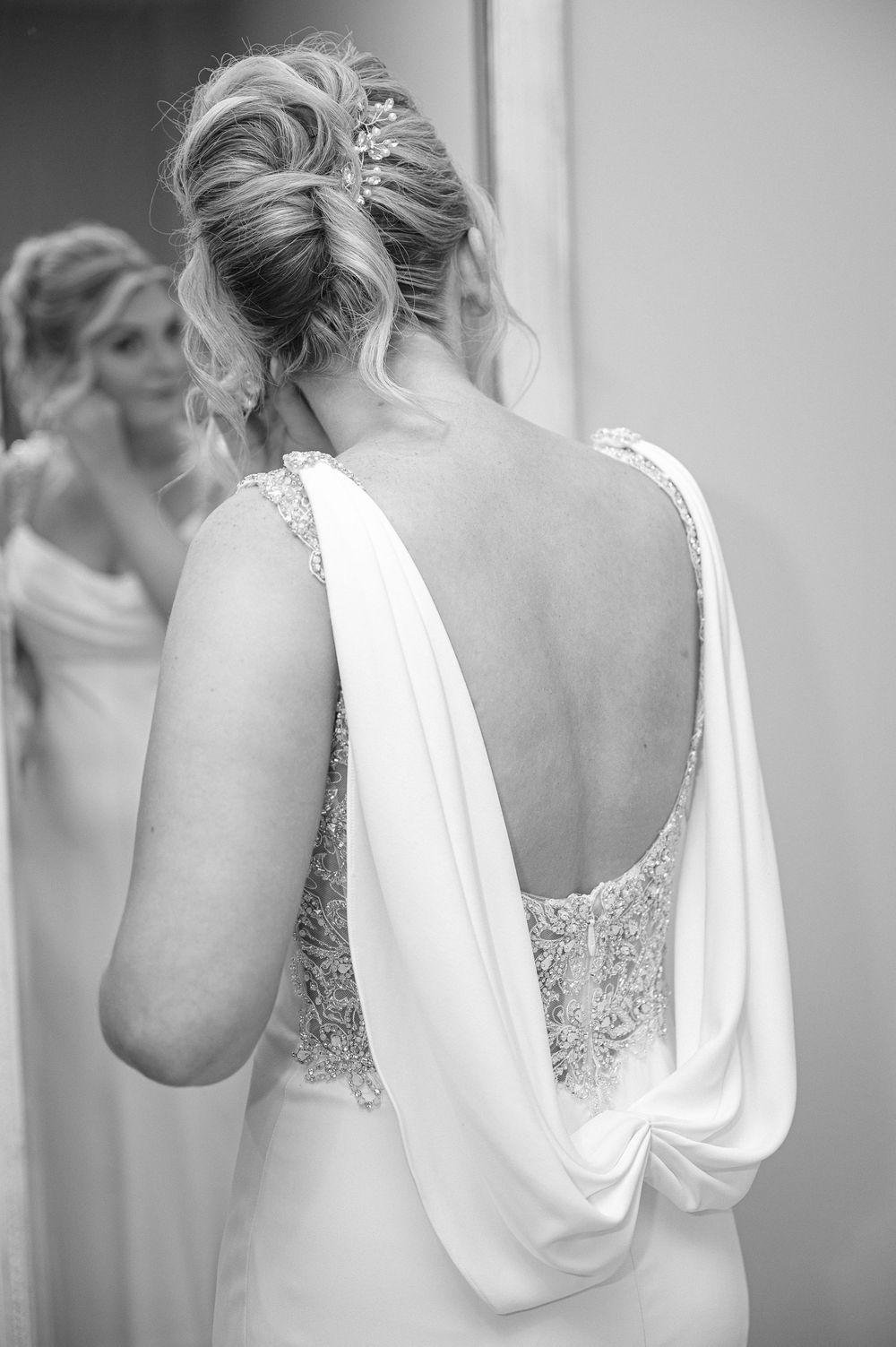 Close-up details of white flowing bridal gown with draped back design.