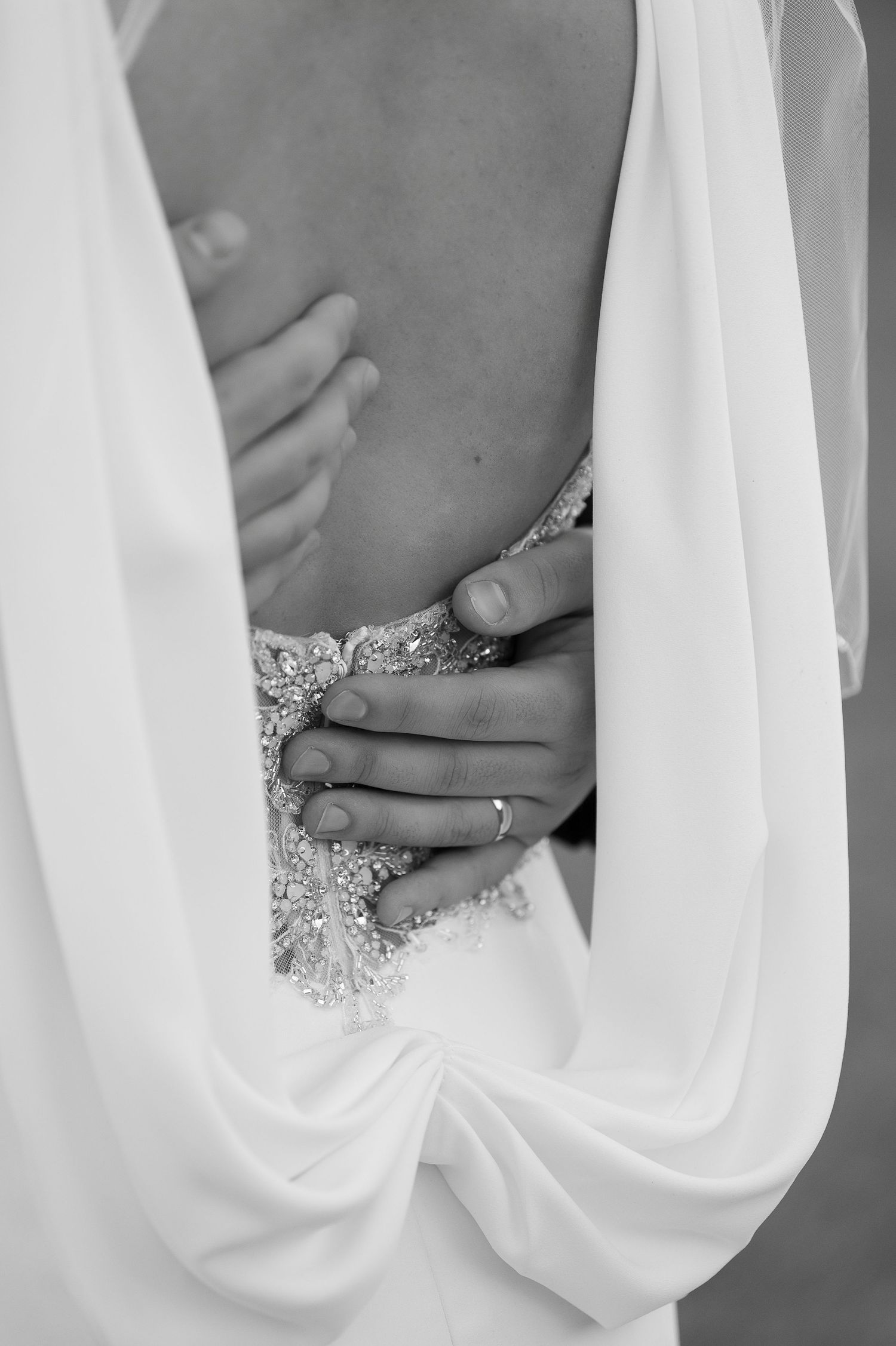 Close-up detail of intricate beading and lace on elegant white wedding dress.