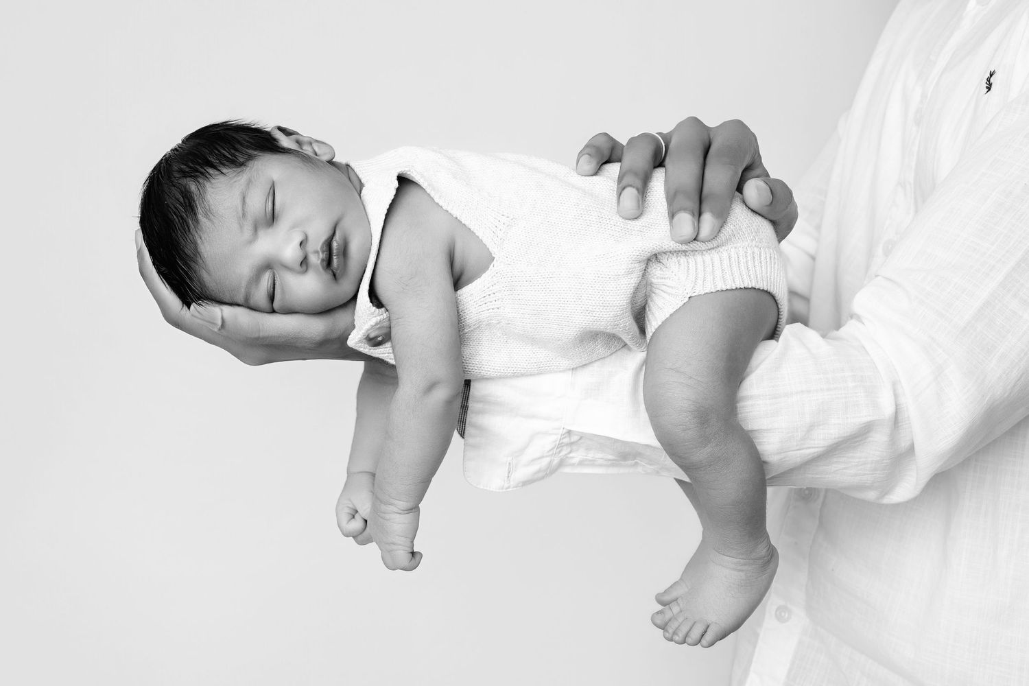 Black and white newborn photography series showing peaceful sleeping poses on white backdrop.
