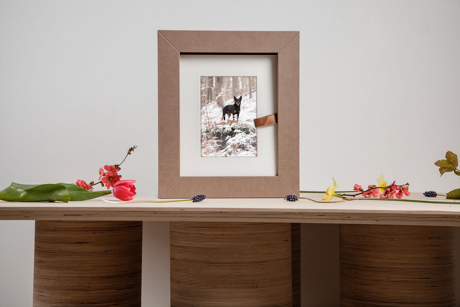 A modern wooden cabinet display wall with framed artwork and decorative items arranged in a minimalist style.