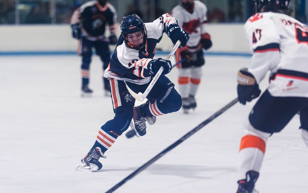 Trojans player battles for the puck against a Cougars defender mid-ice by SportsFox Photography, Hershey PA.