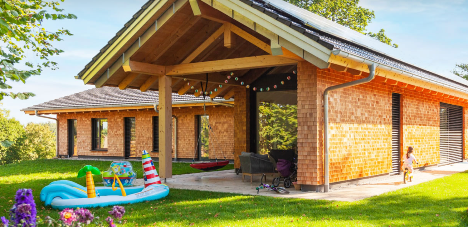 Scenic view of modern wooden cabins nestled in a green hillside with outdoor amenities and recreational facilities.