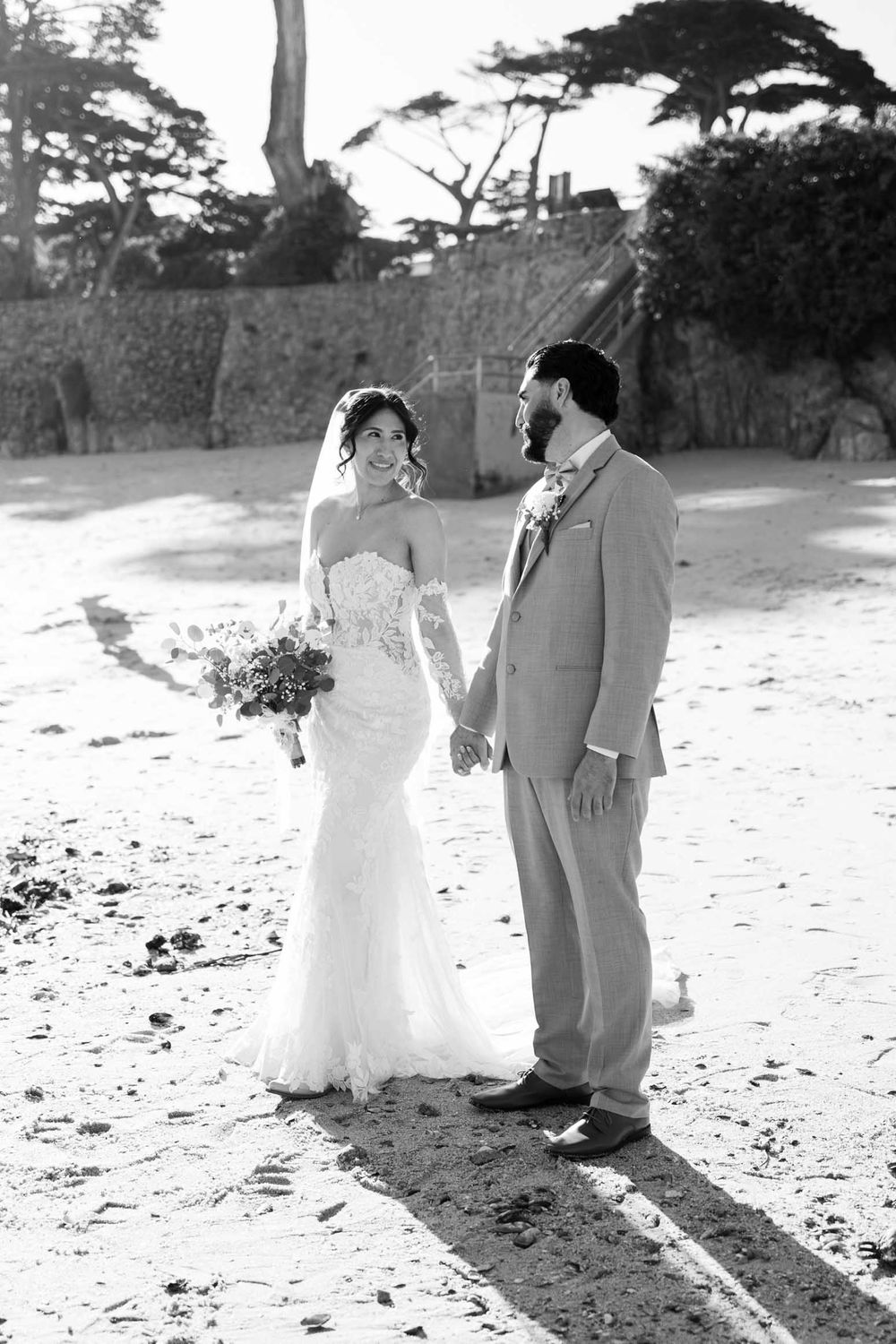 Black and white photos of a couple on a beach with cypress trees in the background.