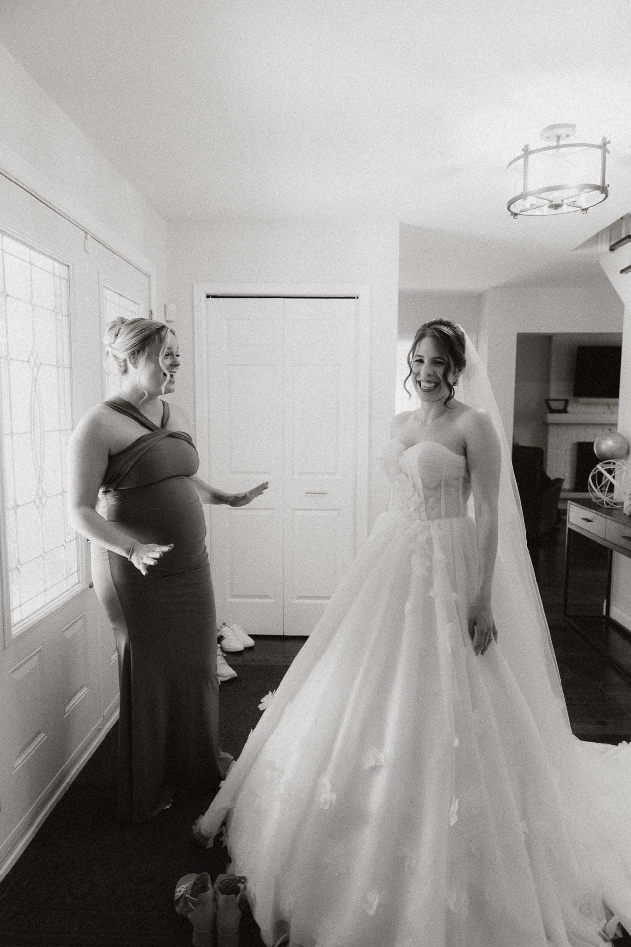 Two women in an elegant room, one wearing a stunning ballgown wedding dress and another in a formal gown.
