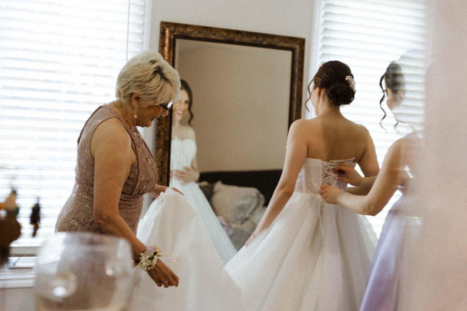 A series of getting ready moments showing a bride in a white wedding dress being helped with final preparations.
