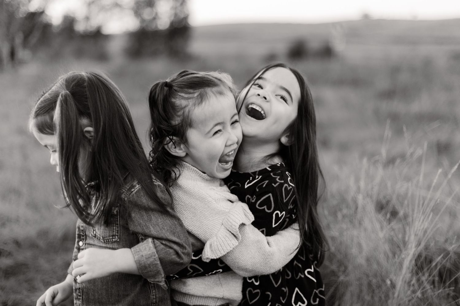 A series of candid black and white family photos showing tender moments between parents and children outdoors.