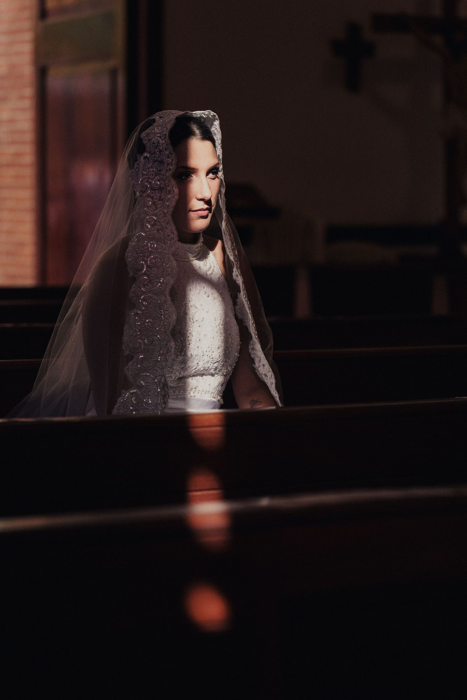 A dramatic moody portrait of a bride wearing a veil in dark atmospheric lighting.