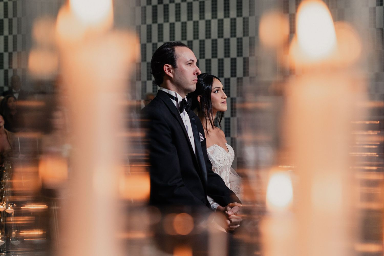 A wedding couple sits together in an intimate moment with candlelight creating a romantic atmosphere.