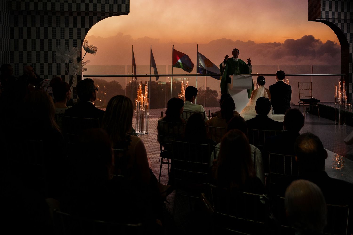 Silhouettes of people gathered on a boat deck at sunset watching the orange and purple sky over the water.