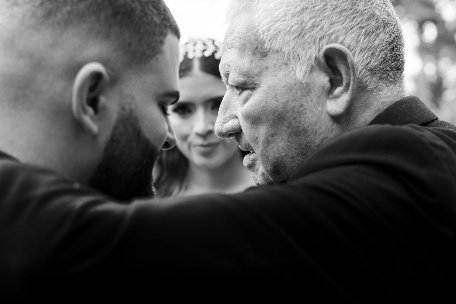 A candid black and white photograph showing three people in close conversation together.