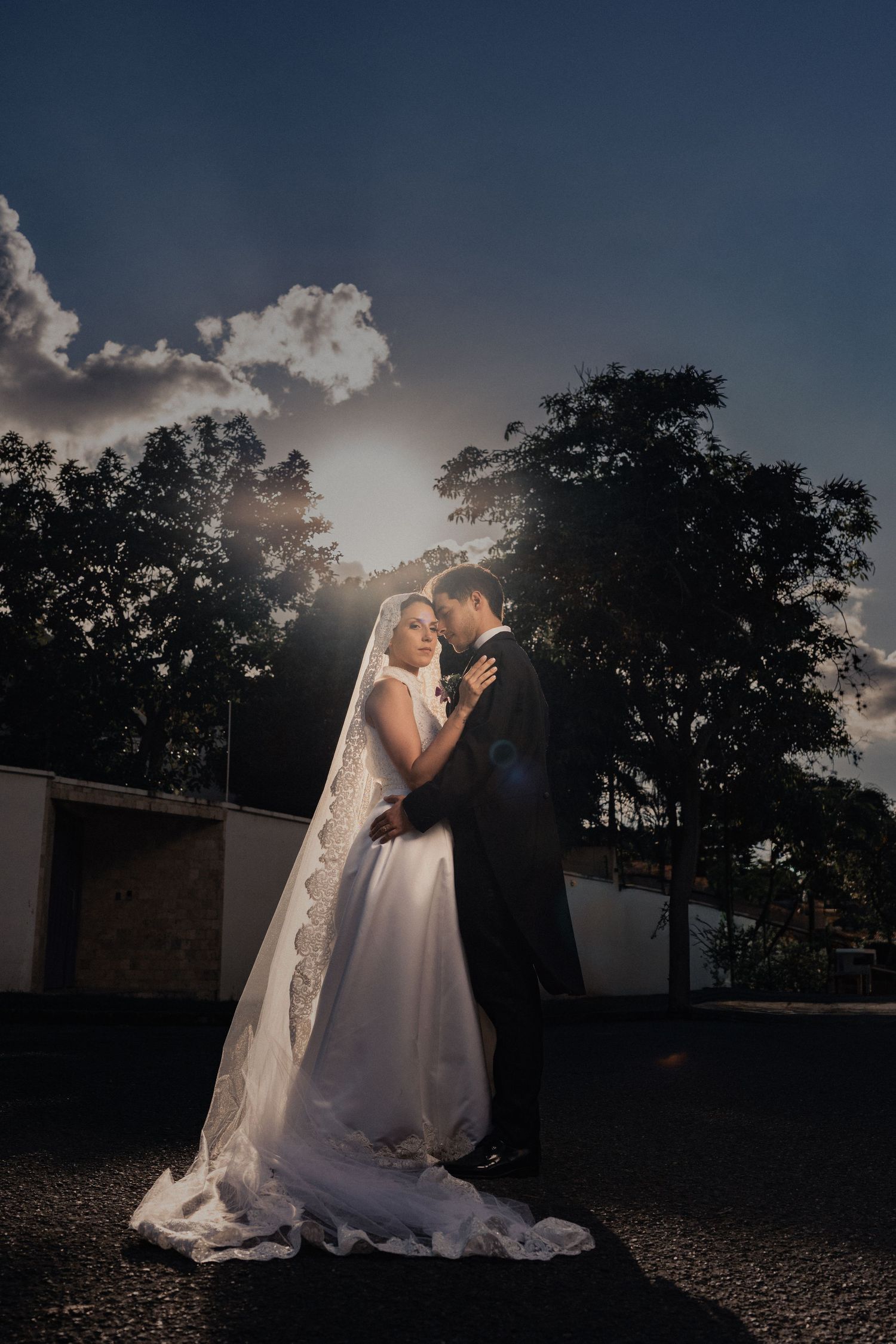 Silhouetted newlyweds sharing an intimate moment against a dramatic sunset sky.