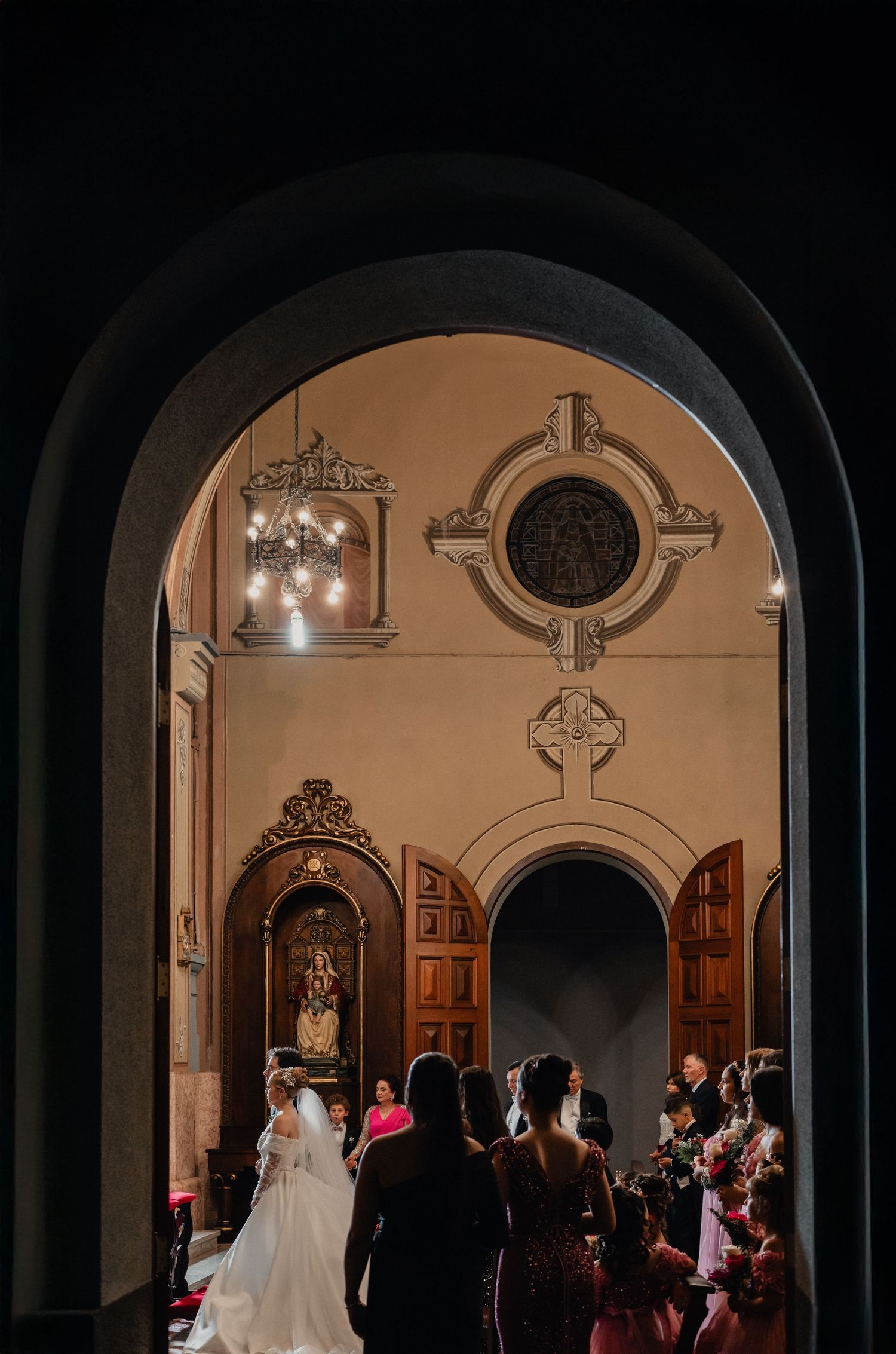 Arched doorways frame an elegant church ceremony with warm lighting.