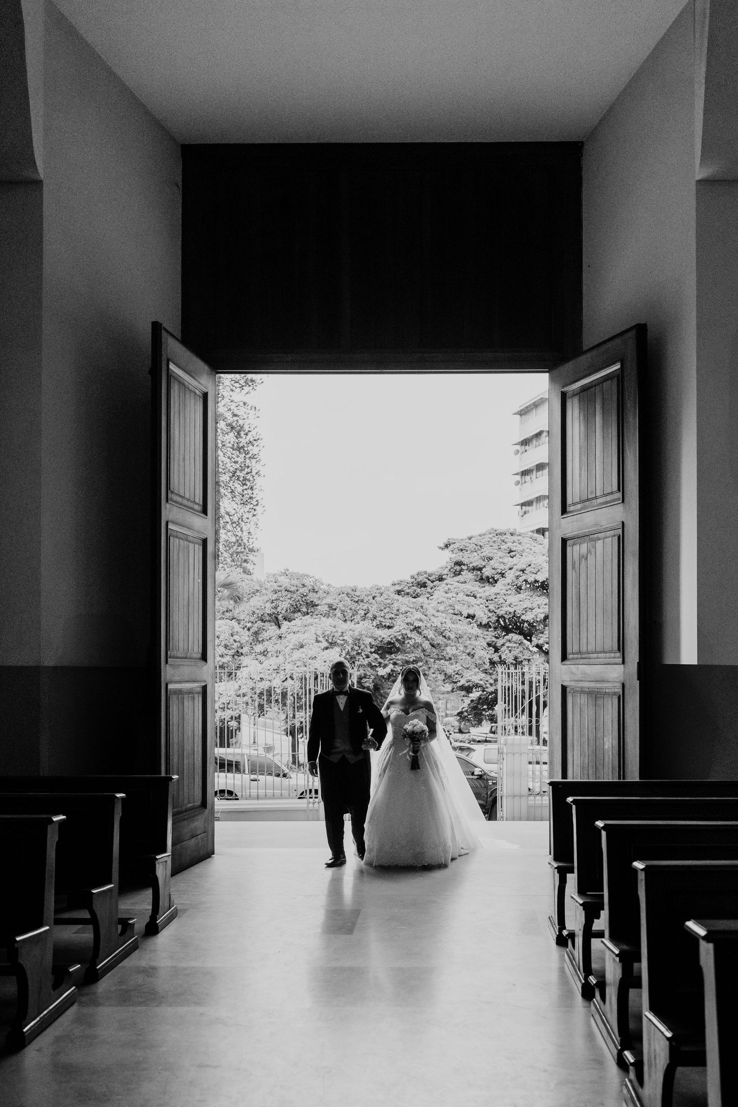 A series of black and white photos showing a wedding couple walking through a church corridor towards bright doorways.
