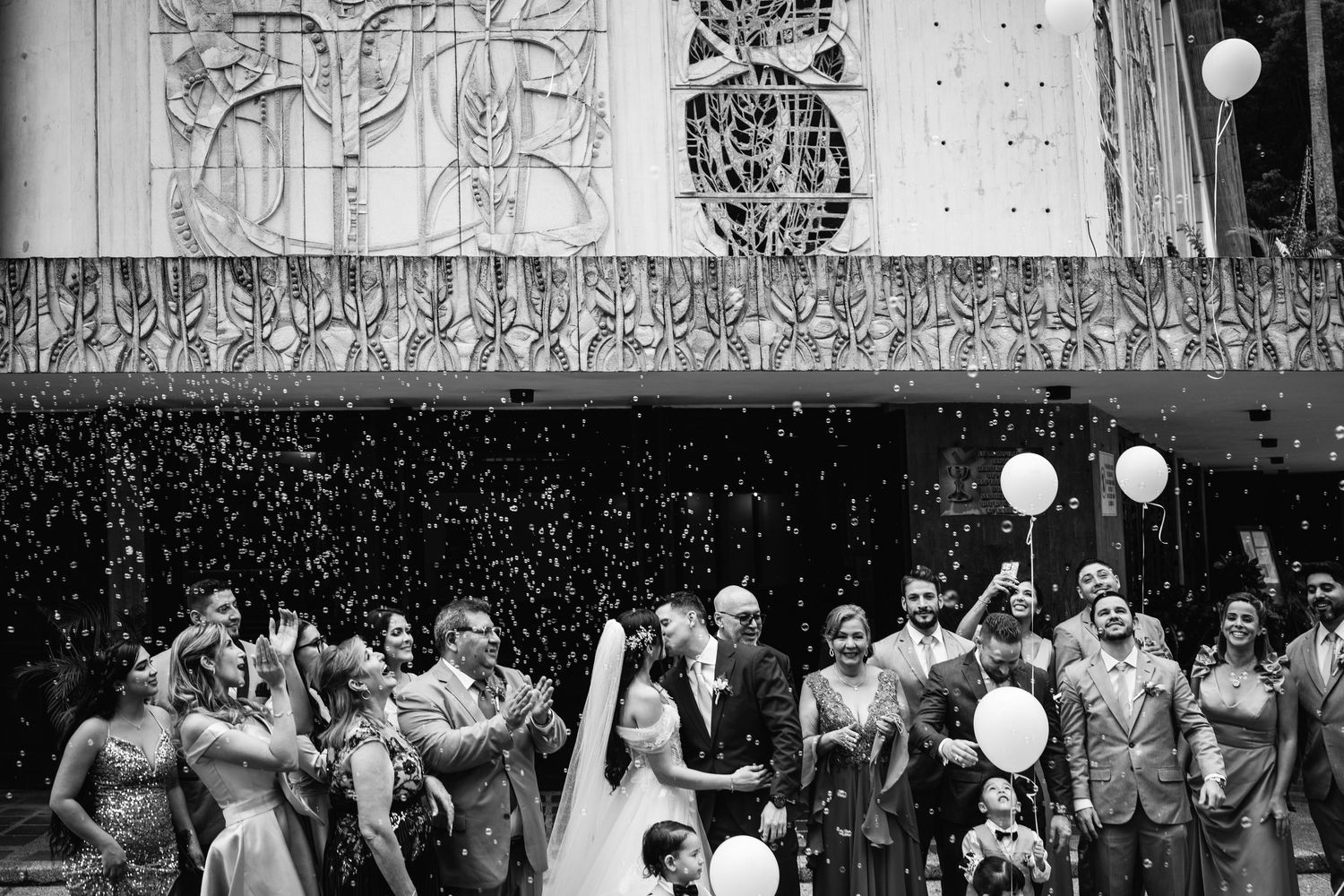 White balloons float upward during an outdoor wedding celebration.