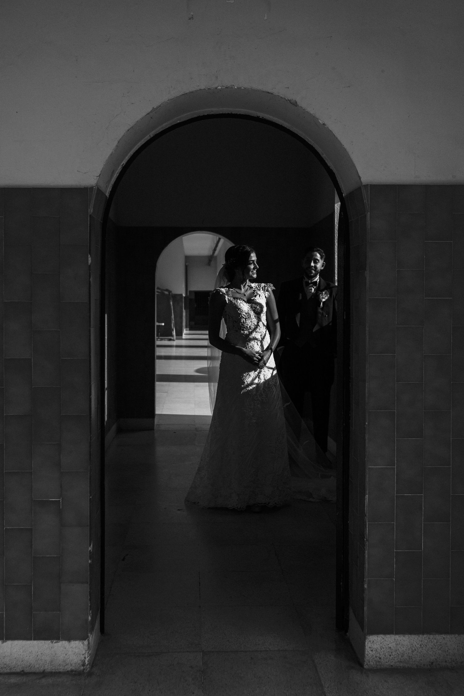 A series of black and white photographs showing silhouettes of people walking through arched hallways and corridors.