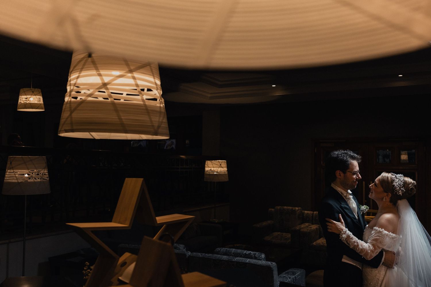 Wedding ceremony in a dimly lit church with dramatic lighting and architectural details.