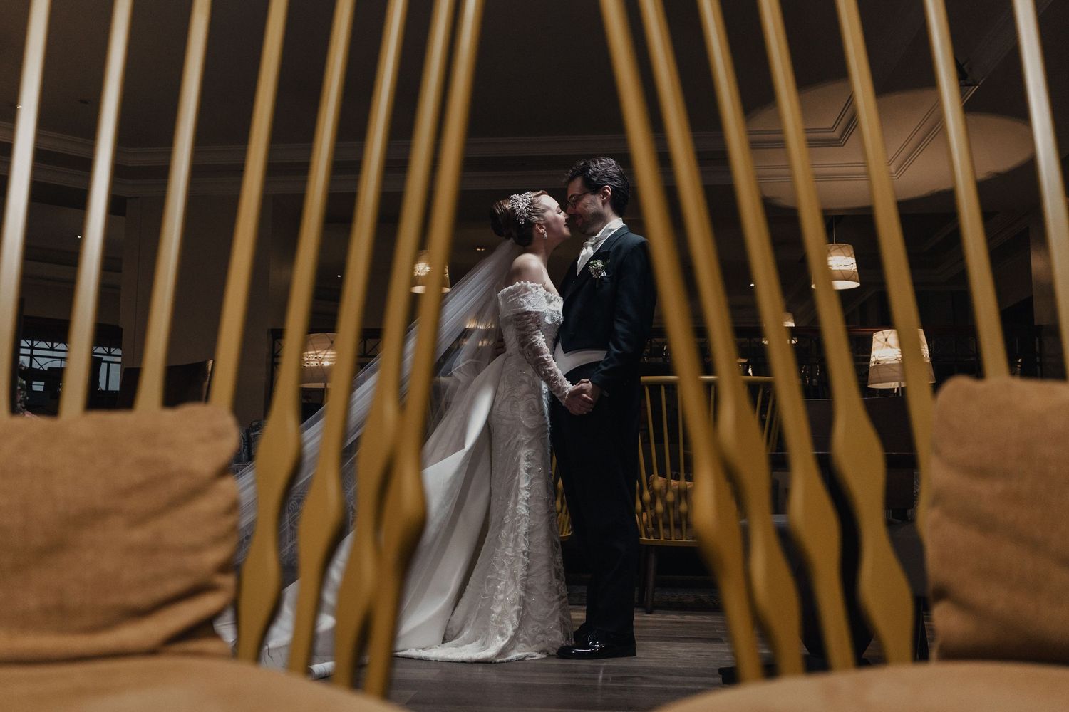 Wedding couple poses elegantly against a backdrop of tall yellow bamboo stalks in a garden setting.