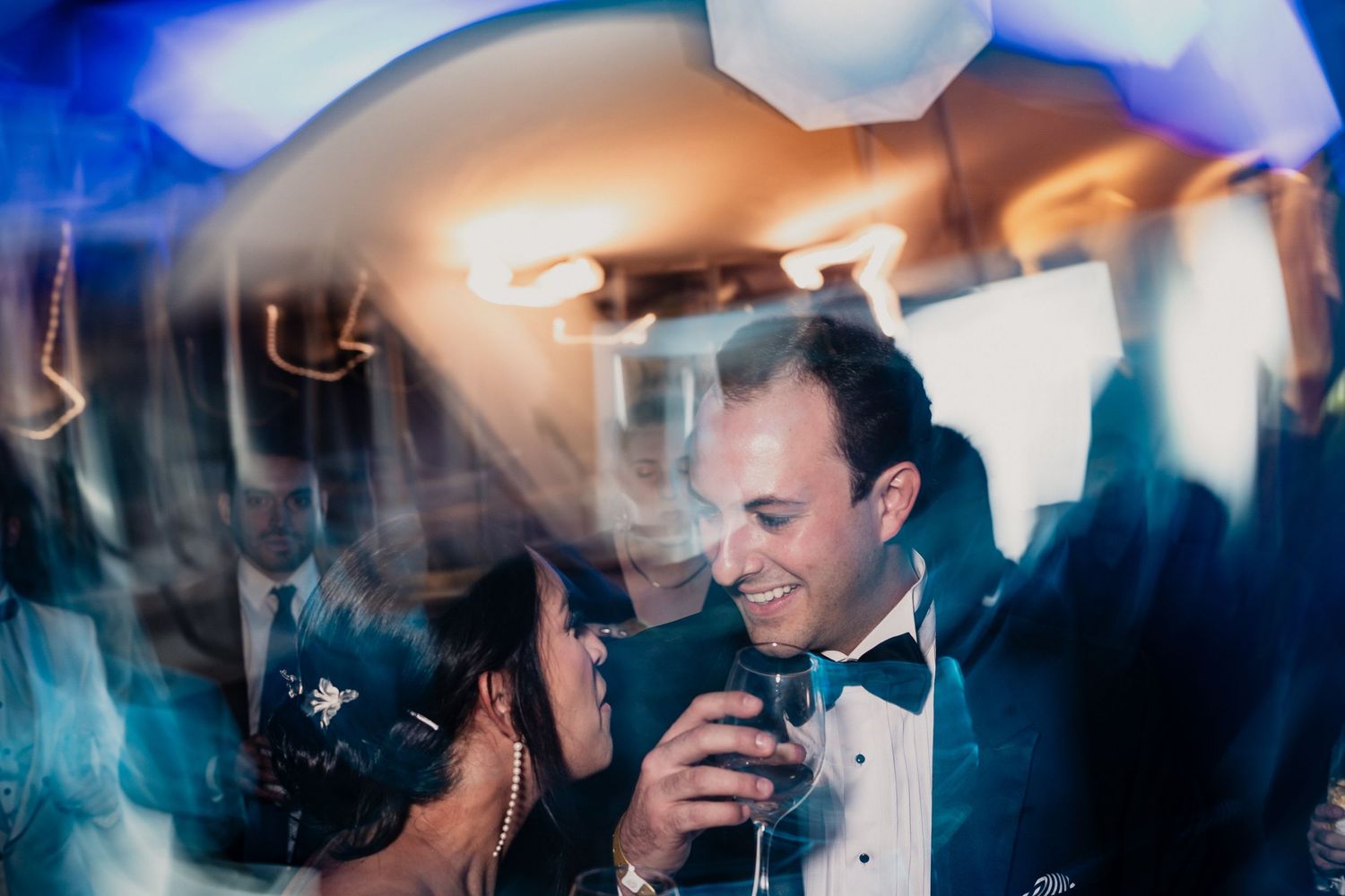 Guests dance and celebrate on a dimly lit dance floor at an elegant wedding reception.