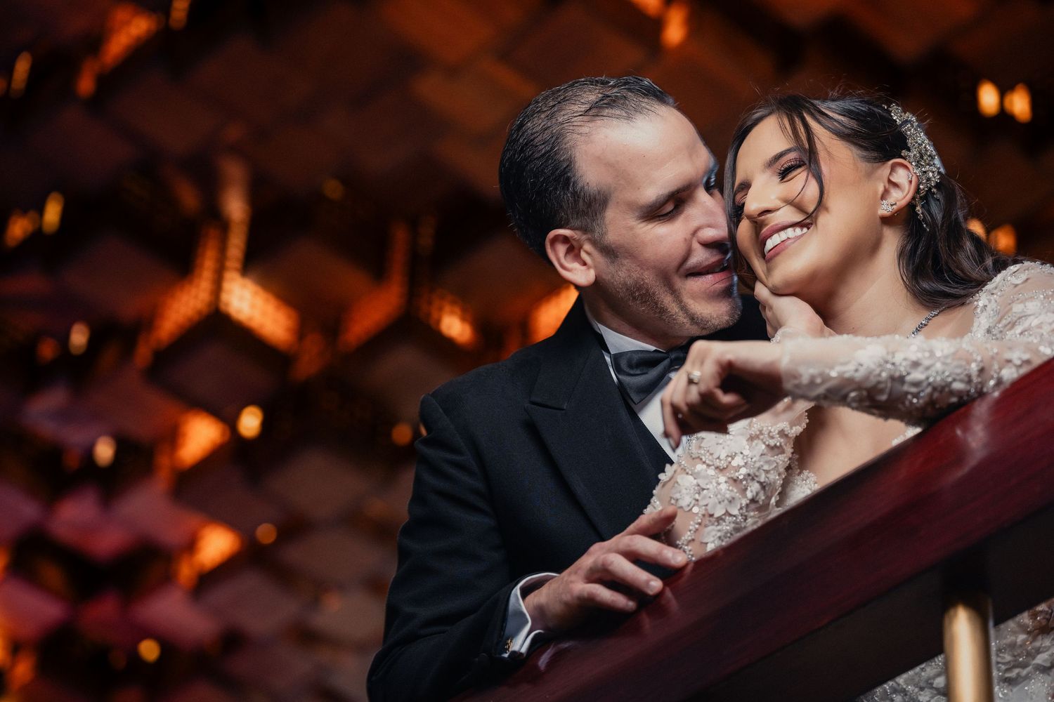 A couple shares an intimate moment during their wedding reception in warm, romantic lighting.