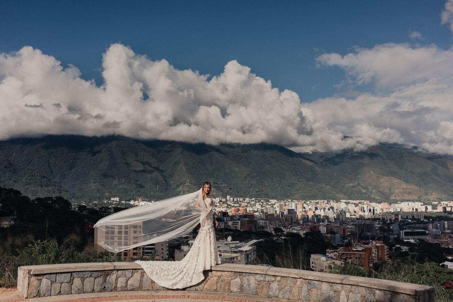 Panoramic mountain landscape with dramatic clouds and cityscape view.