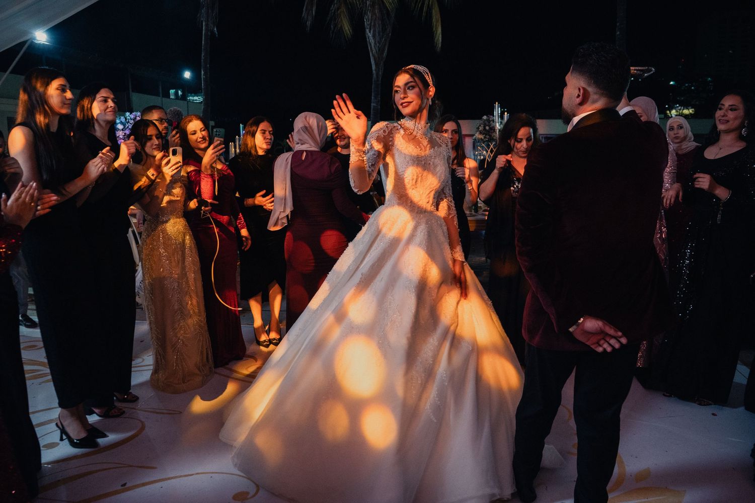 Guests dance together in a dimly lit ballroom during an evening celebration.