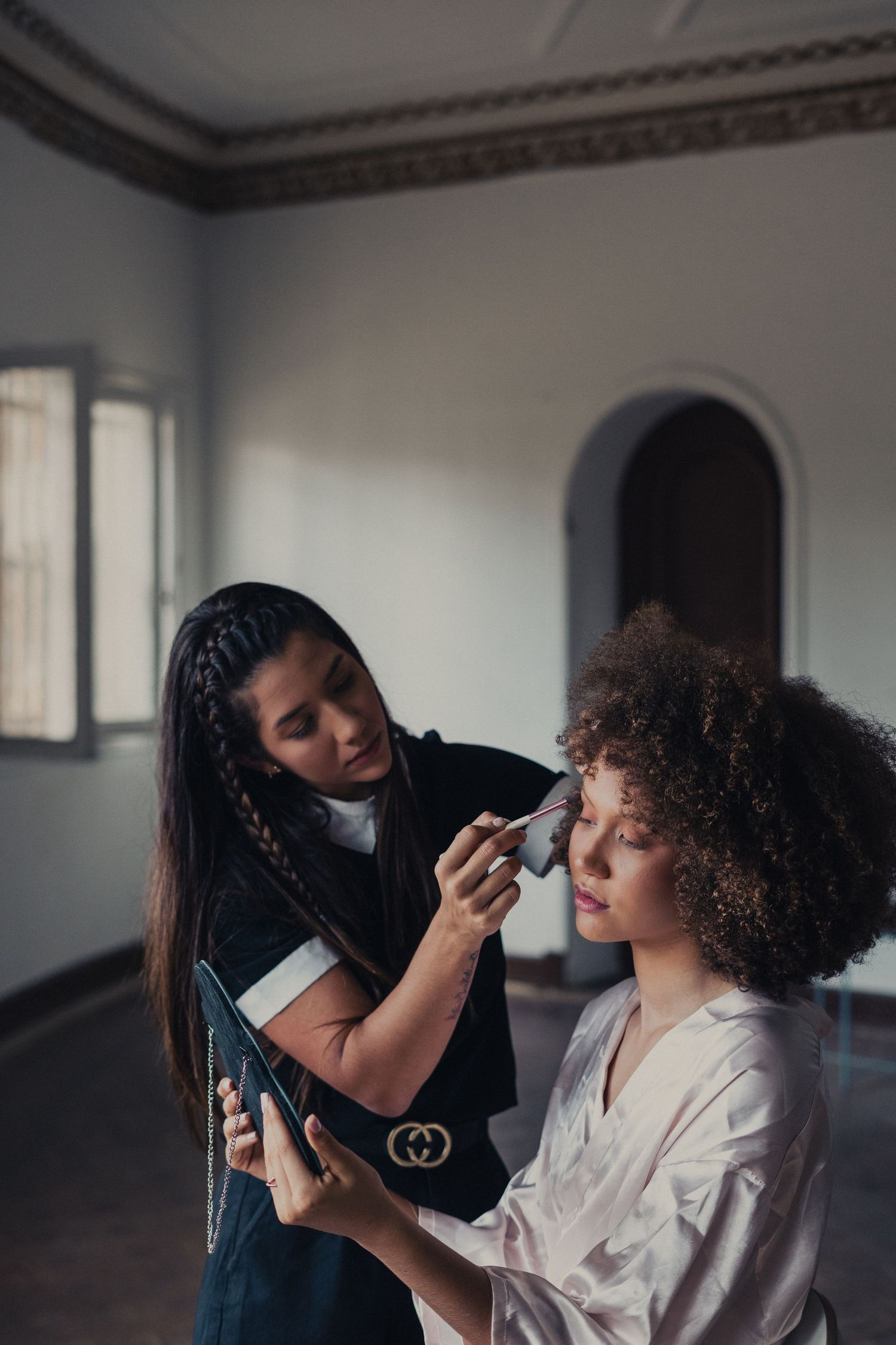 Professional makeup artist applying cosmetics to a client in a bright studio setting.